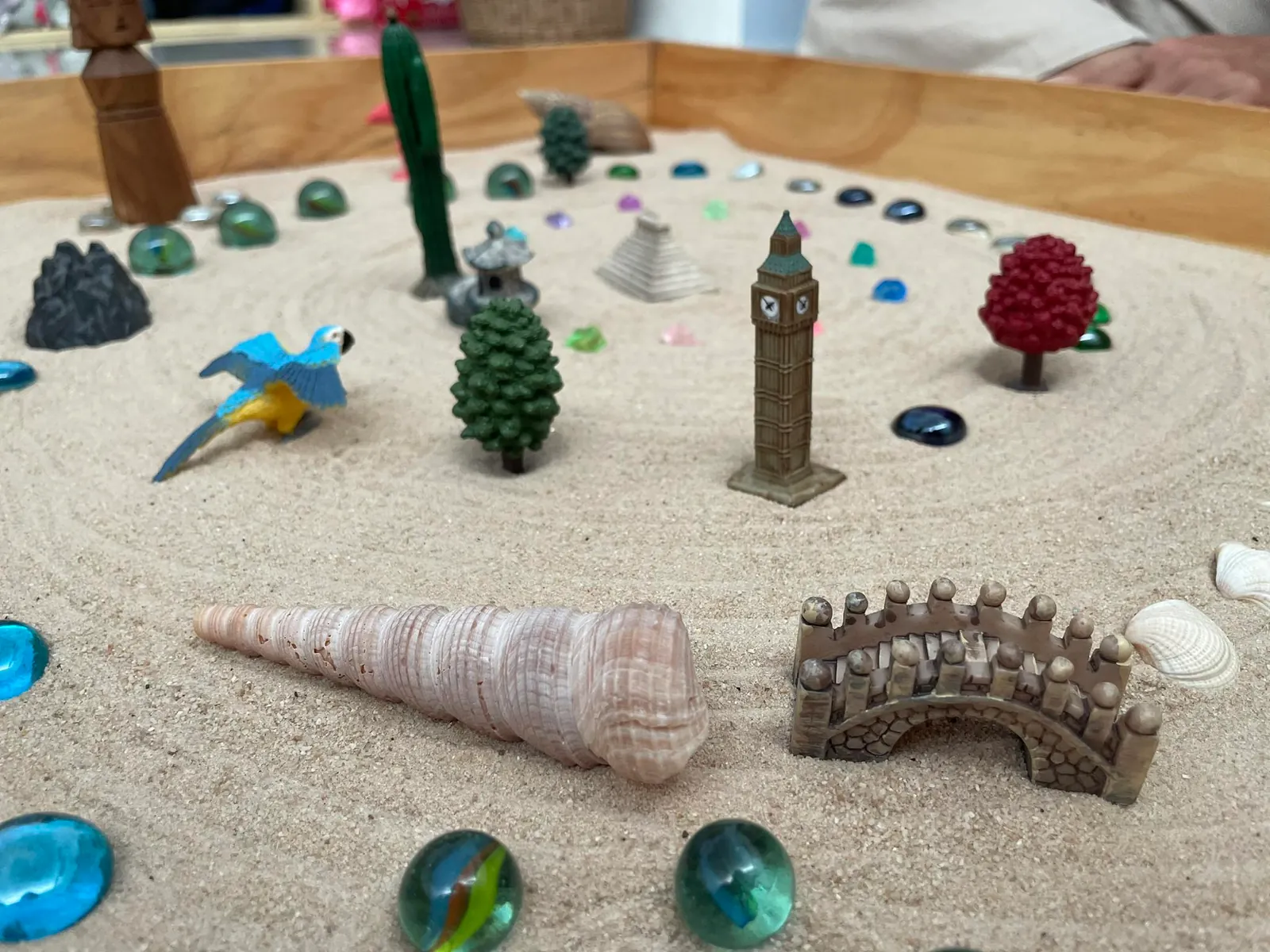 Miniature figures, shells and glass beads arranged in a sand tray
