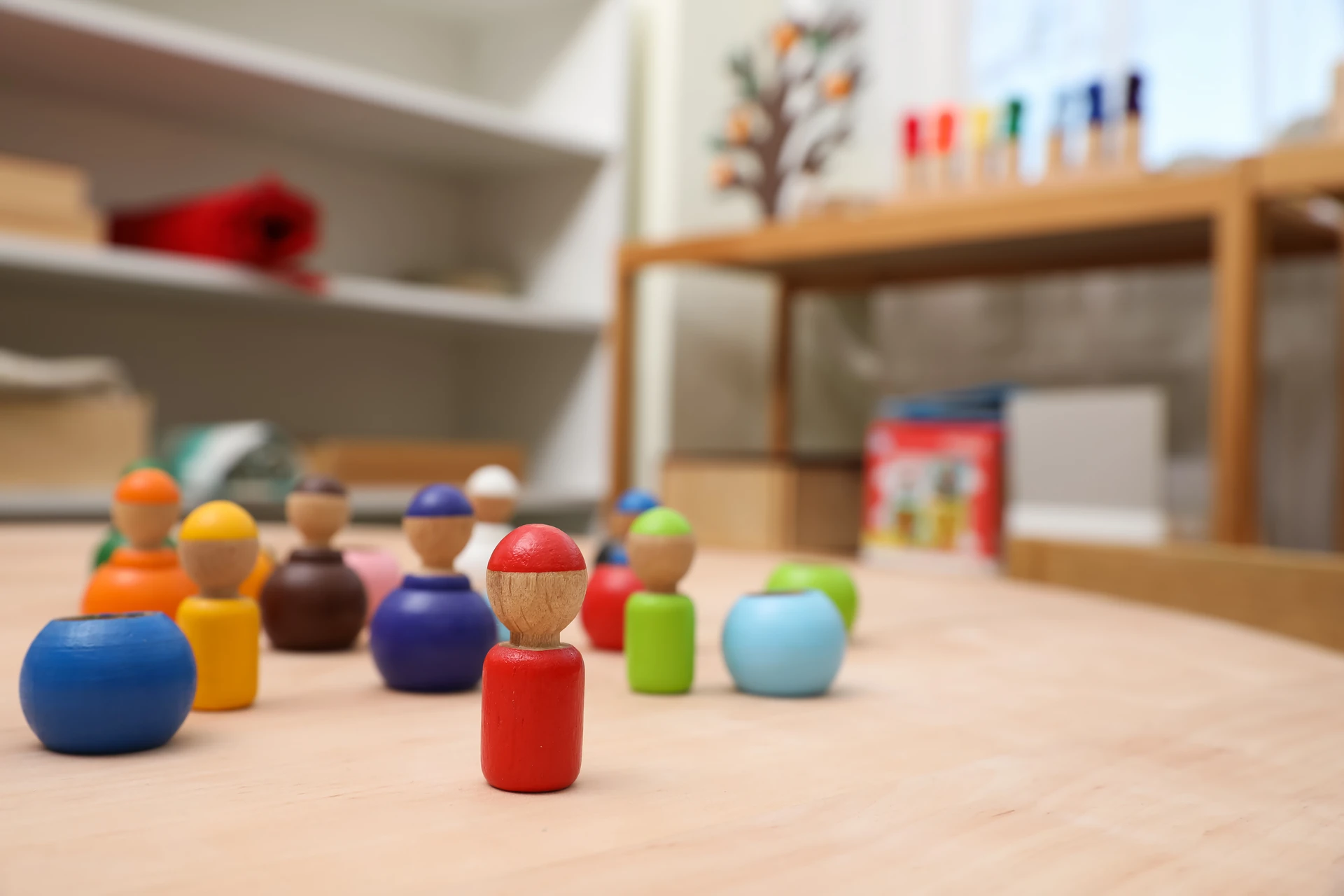 Brightly painted wooden peg dolls on a table in an early years classroom